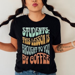 May include: A black t-shirt with a retro-style graphic that reads "Students: This lesson is brought to you by coffee".