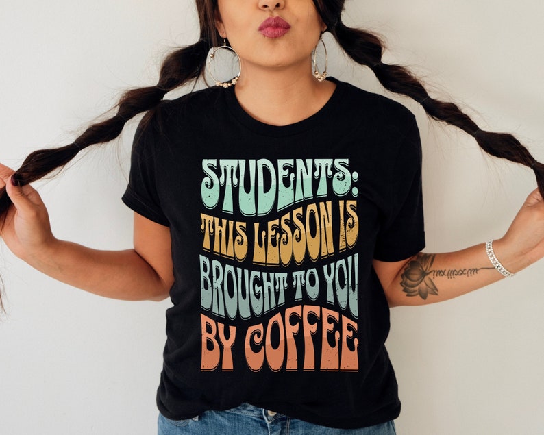 May include: A black t-shirt with a retro-style graphic that reads "Students: This lesson is brought to you by coffee".