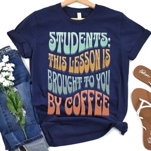 May include: Navy blue t-shirt with a retro-style graphic that reads "Students: This lesson is brought to you by coffee".