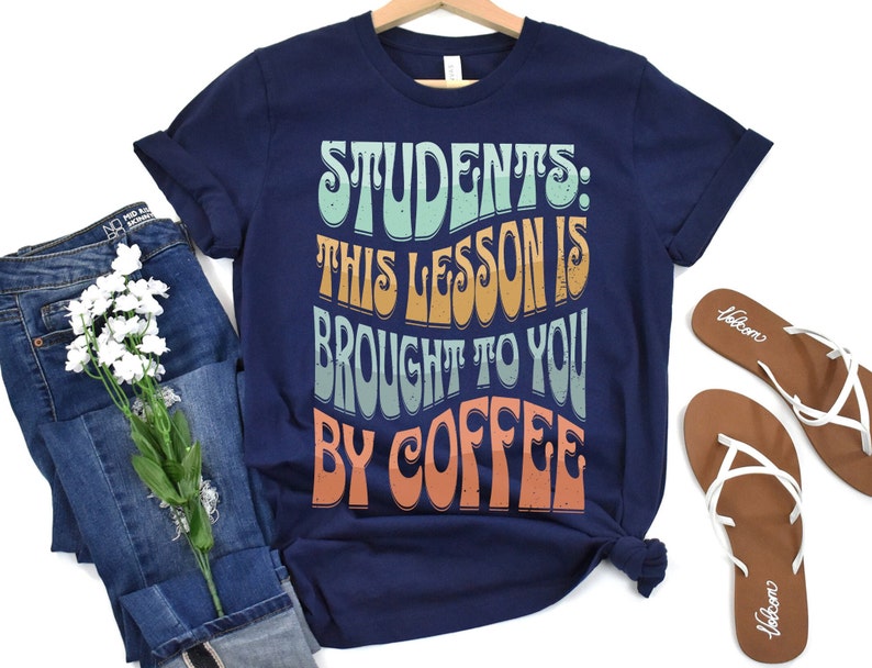 May include: Navy blue t-shirt with a retro-style graphic that reads "Students: This lesson is brought to you by coffee".