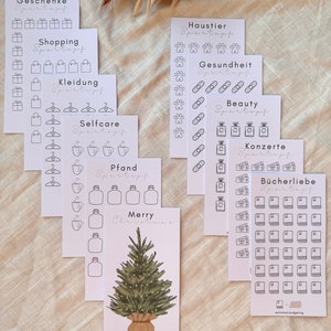 Könnte beinhalten: Satz von 10 druckbaren Karten mit Schwarzweißillustrationen für einen Spar-Tracker. Die Karten sind mit Kategorien wie "Geschenke", "Einkaufen", "Kleidung", "Selbstpflege", "Pfand", "Haustiere", "Gesundheit", "Beauty", "Konzerte" und "Buchliebe" beschriftet. Die letzte Karte zeigt eine Weihnachtsbaumillustration und den Text "Frohe Weihnachten".