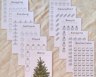 May include: Set of 10 printable cards with black and white illustrations for a savings tracker. The cards are labeled with categories such as "Gifts", "Shopping", "Clothing", "Selfcare", "Pfand", "Pets", "Health", "Beauty", "Concerts", and "Book Love". The last card features a Christmas tree illustration and the text "Merry Christmas".