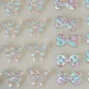 May include: Assortment of iridescent butterfly and bow-shaped embellishments. The embellishments are made of clear plastic with a rainbow iridescent finish.