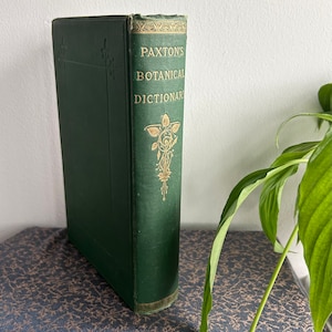May include: A vintage green hardback book titled "Paxton's Botanical Dictionary". The book has gold lettering and decorative floral designs on the spine.