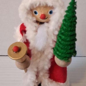 May include: A set of three ceramic mugs with a speckled, cream-colored glaze. Each mug features a different hand-painted design: a blue and green leaf, a yellow flower, and a red berry. The mugs have a simple, modern design.