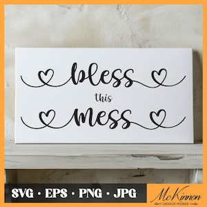 May include: White sign with black text that reads "Bless this mess" with a heart on either side of the words.