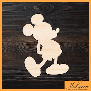Peut inclure: Découpe en bois de Mickey Mouse en position de marche. La découpe en bois clair est placée sur un fond à grain de bois foncé. Le coin inférieur droit porte la mention "McKinnon Design Works".