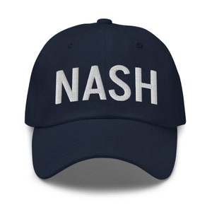 Può includere: Un cappello da baseball blu navy con testo ricamato in bianco che recita "NASH".