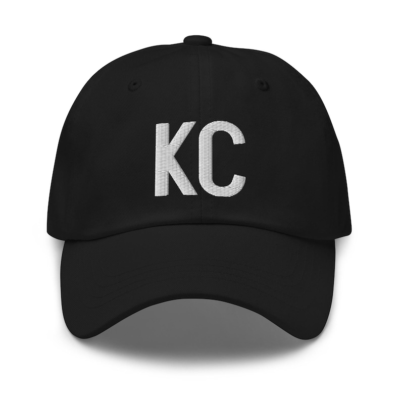 May include: A black baseball cap with a white embroidered "KC" on the front.
