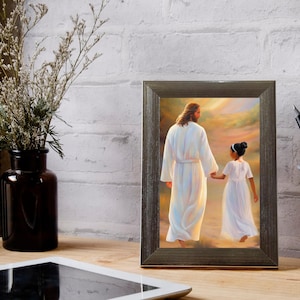 May include: A framed painting of a man and a young girl walking hand-in-hand on a path. The man is wearing a white robe and the girl is wearing a white dress. The painting is set against a background of a golden sunset.