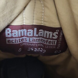 Pu&ograve; includere: Primo piano di un'etichetta in pelle marrone con testo bianco che recita "BamaLams echtes Lammfell" e "Obermaterial Leder". L'etichetta include anche i numeri "8 24 3829 62" e "Made in Germany".