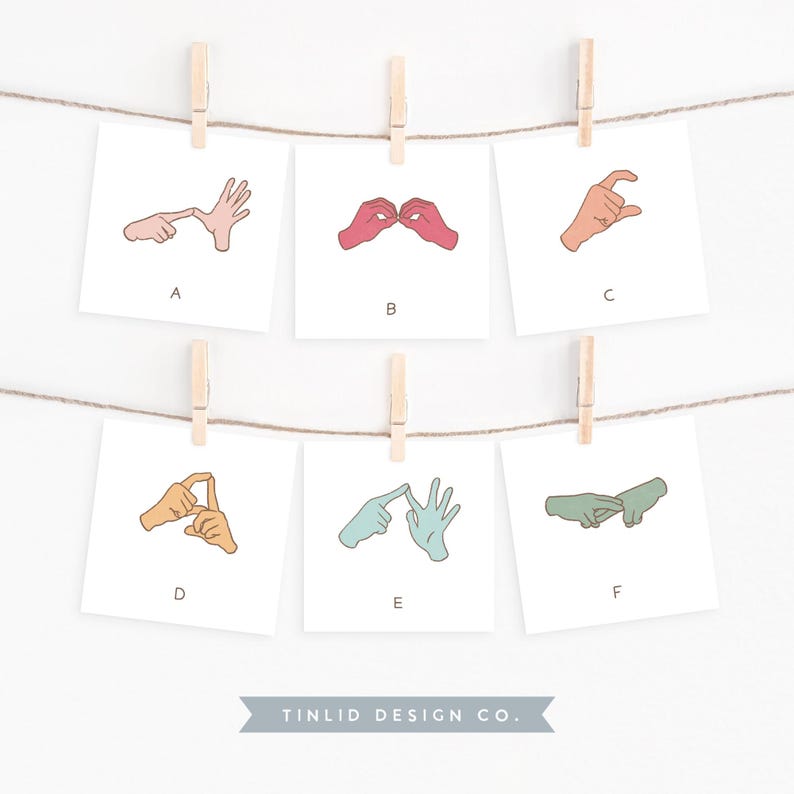 Close-up of six illustrated flash cards, each featuring hand-drawn AUSLAN sign language for letters A to F, clipped on a string. Ideal for teaching sign language basics to children in a vibrant classroom setting.