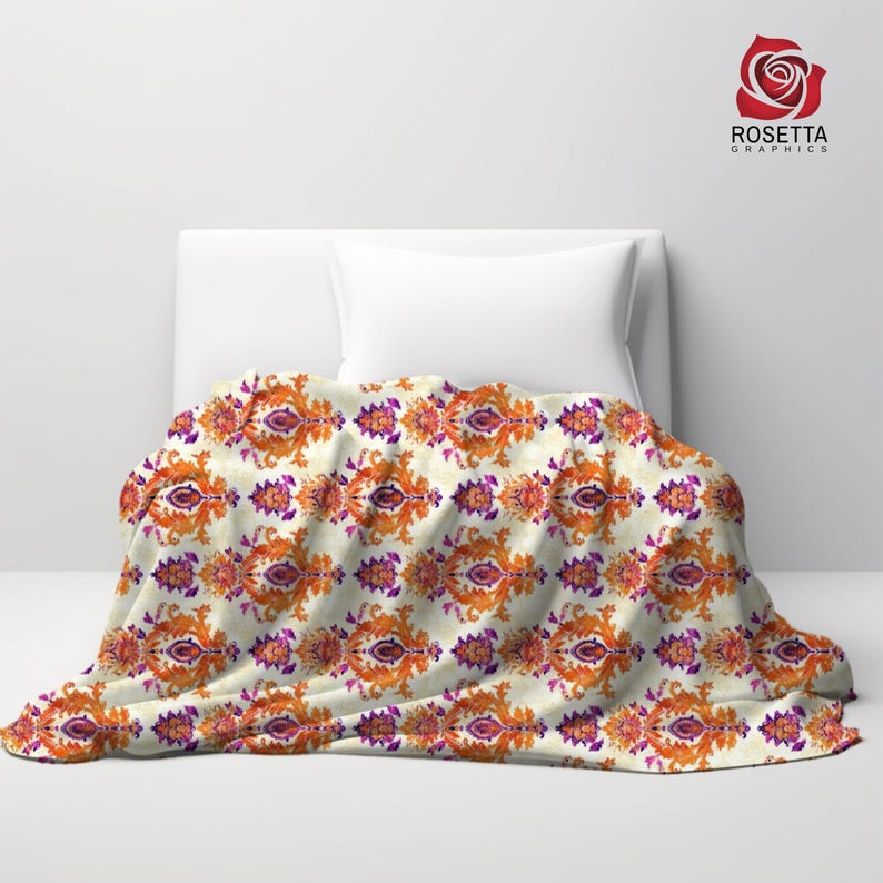 May include: A white throw blanket with a repeating pattern of orange, purple, and gold floral designs. The blanket is folded and draped over two white pillows on a bed.