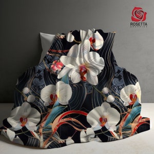 May include: A black and white throw blanket with a floral pattern of white orchids and gold accents. The blanket features a repeating pattern of orchids and gold lines on a black background.
