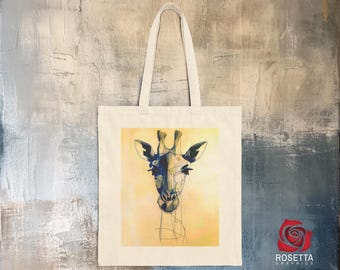 May include: A white tote bag with a graphic of a giraffe's head in blue and yellow on a yellow background. The giraffe's eyes are closed and it has a long neck.