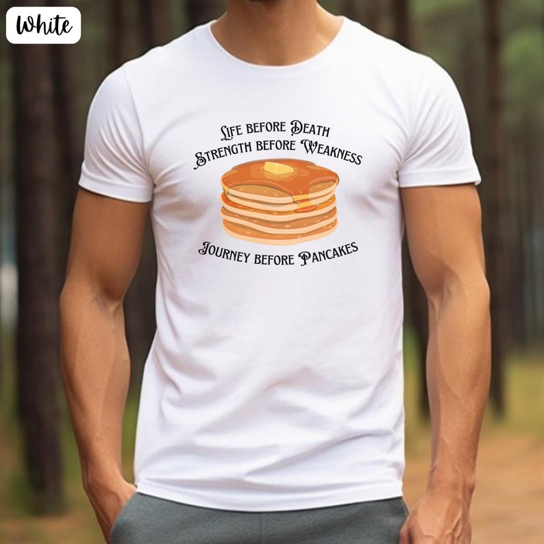 May include: White t-shirt with a graphic of a stack of pancakes and the text "Life Before Death, Strength Before Weakness, Journey Before Pancakes".