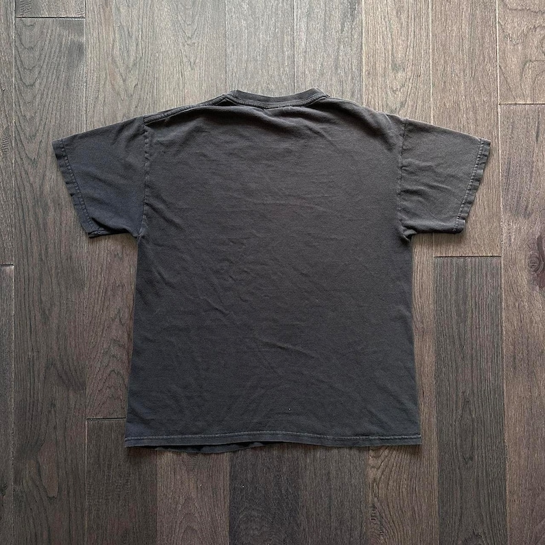 Puede incluir: Una camiseta negra de cuello redondo y mangas cortas.