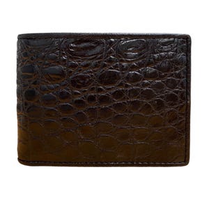 May include: A dark brown, rectangular wallet with a textured, crocodile-like pattern. The wallet is made of a shiny material and has a classic, bi-fold design. The wallet is shown against a white background.