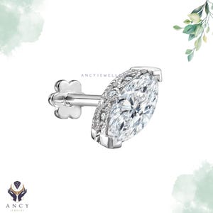 May include: A silver-toned stud earring featuring a marquise-cut clear stone surrounded by a halo of small pavé-set stones. The post has a flower-shaped backing and the text ANCYJEWELLERY is visible on the metal setting of the earring.