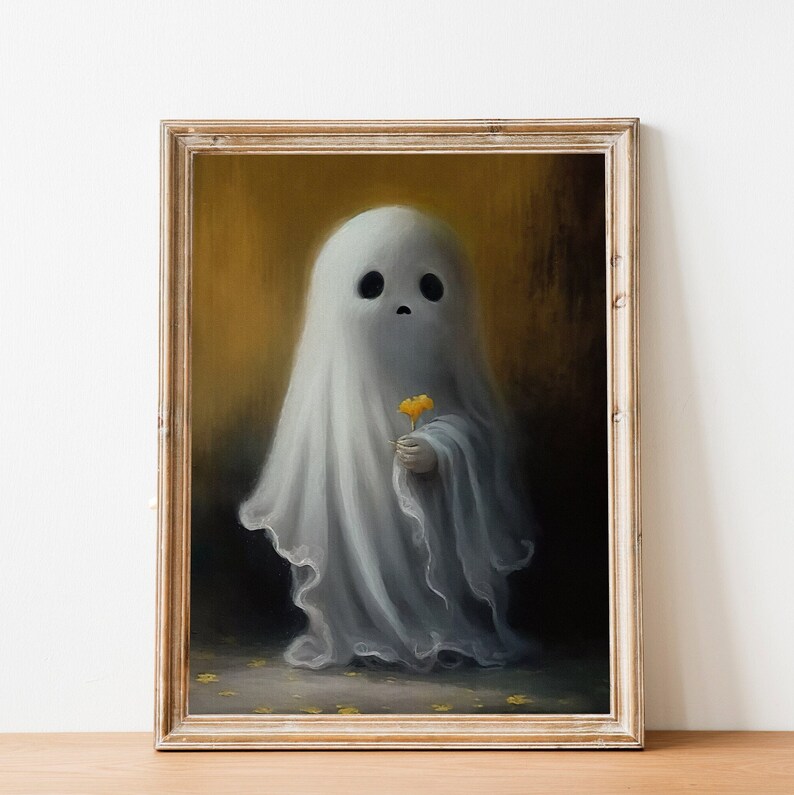 May include: A framed print featuring a whimsical ghost holding a yellow flower. The ghost is draped in a white sheet with dark eyes and a small mouth. The artwork has a vintage aesthetic with a gold-colored frame and a warm, golden background.