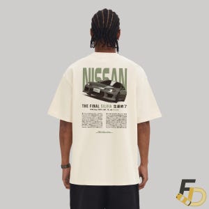May include: A cream-colored t-shirt with a graphic print of a silver Nissan Silvia car. The text "NISSAN" is printed in green above the car, and the text "THE FINAL SILVIA 生產終了" is printed in green below the car. The text "2002.aug. 100PS, 6MT, FR, and Passion" is printed in black below the car. The text "Silvia" is printed in black at the bottom of the graphic.