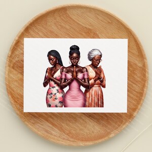 May include: A print featuring three women with their hands clasped in prayer. The women are depicted in a variety of dresses, including a floral print and a pink dress. The image is set against a white background and presented on a wooden tray.