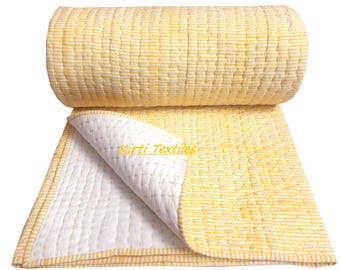 May include: A rolled-up yellow and white striped quilt with a section unfolded, showing a white interior. The quilt has a stitched pattern and the text "Kirti Textiles".