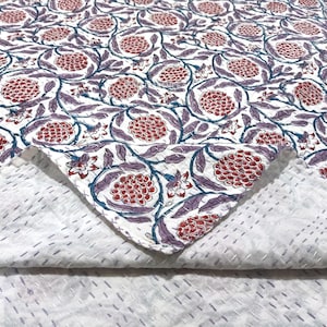 Puede incluir: Un edredón blanco con un patrón repetitivo de diseños florales rojos y morados. El edredón presenta un estampado floral detallado con un reverso blanco contrastante y costuras visibles. La estética general es una mezcla de diseño tradicional y floral.