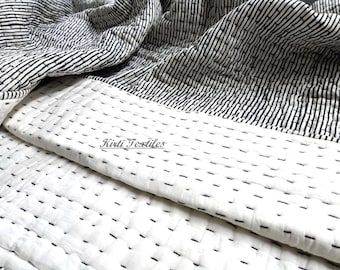 May include: A white and black striped cotton quilt with a simple stitch pattern. The quilt is folded in half, showing the white side with the stitching. The text "Kirti Textiles" is visible on the quilt.