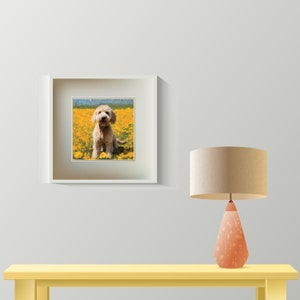 May include: A framed print of a light brown dog sitting in a field of yellow flowers. The dog is looking directly at the camera and has a happy expression on its face.