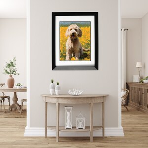 May include: A framed photograph of a light brown dog sitting in a field of yellow flowers. The dog is smiling and looking directly at the camera.
