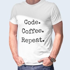 May include: White t-shirt with the text "Code. Coffee. Repeat." in black, typewriter-style font. The shirt is plain and simple, with a crew neck. The image shows the shirt on a person.