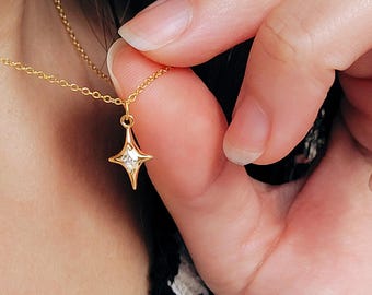 Puede incluir: Un collar de cadena dorada con un pequeño colgante en forma de estrella con un cristal transparente en el centro.