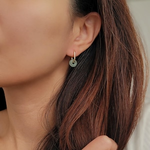 Close-up of a woman wearing green jade link hoop earrings, showcasing their elegant and minimalist design.