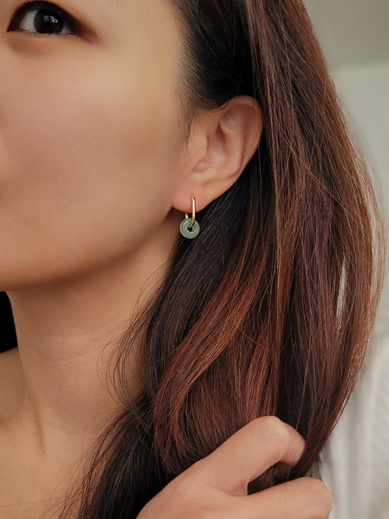 Close-up of a woman wearing green jade link hoop earrings, showcasing their elegant and minimalist design.