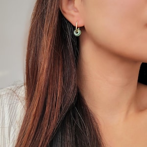 Elegant green jade hoop earrings with gold accents, worn by a model, adding a subtle yet sophisticated touch to her look.