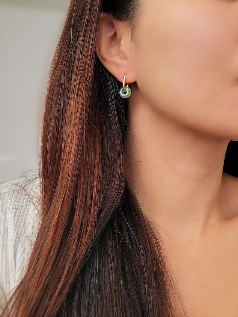 Elegant green jade hoop earrings with gold accents, worn by a model, adding a subtle yet sophisticated touch to her look.