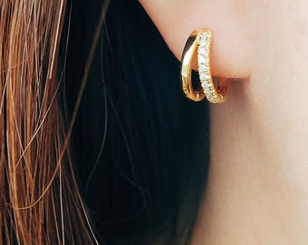 May include: Gold hoop earrings with a row of small clear stones around the top edge.