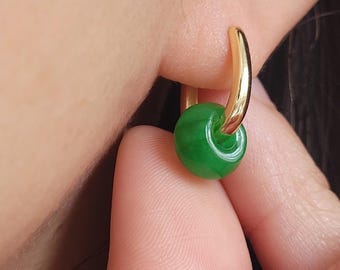 Può includere: Orecchini a cerchio in oro con un ciondolo in giada verde. La perla è rotonda e ha una superficie liscia e lucida.