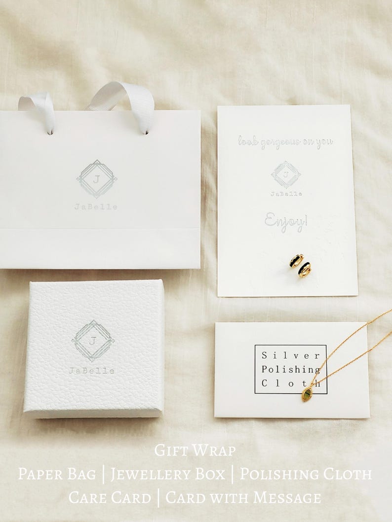 May include: A white gift bag with a silver logo that says "JaBelle" and a white jewelry box with the same logo. There is a white card with the text "look gorgeous on you" and "Enjoy!" and a silver polishing cloth with the text "Silver Polishing Cloth". The text "GIFT WRAP" is printed below the image. The text "PAPER BAG | JEWELLERY BOX | POLISHING CLOTH" is printed below the text "GIFT WRAP". The text "CARE CARD | CARD WITH MESSAGE" is printed below the text "PAPER BAG | JEWELLERY BOX | POLISHING CLOTH".