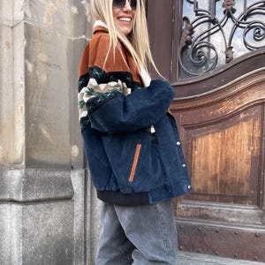 Peut inclure: Veste en velours côtelé bleu marine, marron et vert avec un col en fausse fourrure blanche. Le bas est composé d'un jean gris et de bottines en daim marron. Une tenue décontractée et élégante.