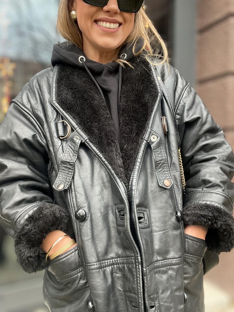 May include: A black leather jacket with a fur-lined collar and cuffs. The jacket has a zipper closure and multiple pockets.
