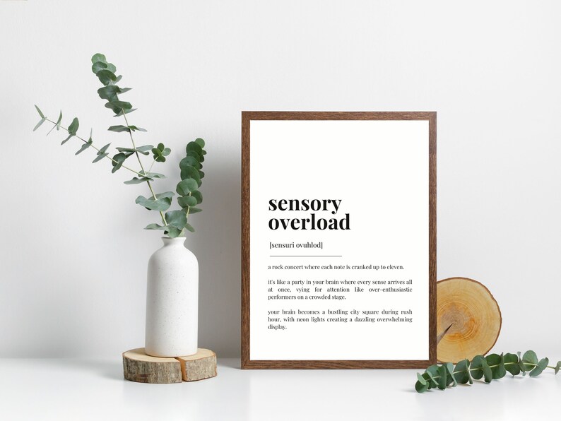 May include: A framed print with a white background and black text. The text reads "sensory overload" and defines the term as "a rock concert where each note is cranked up to eleven." The definition continues, comparing the experience to a party in the brain where every sense arrives at once, vying for attention like over-enthusiastic performers on a crowded stage. The definition concludes by describing the brain as a bustling city square during rush hour, with neon lights creating a dazzling, overwhelming display.