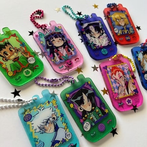 May include: A collection of rectangular acrylic keychains shaped like vintage mobile phones, each featuring colorful anime-style character illustrations, glitter accents, and small ball chains. The designs include various characters with numbers like 405, 301, 44, and 99 printed on the surface.
