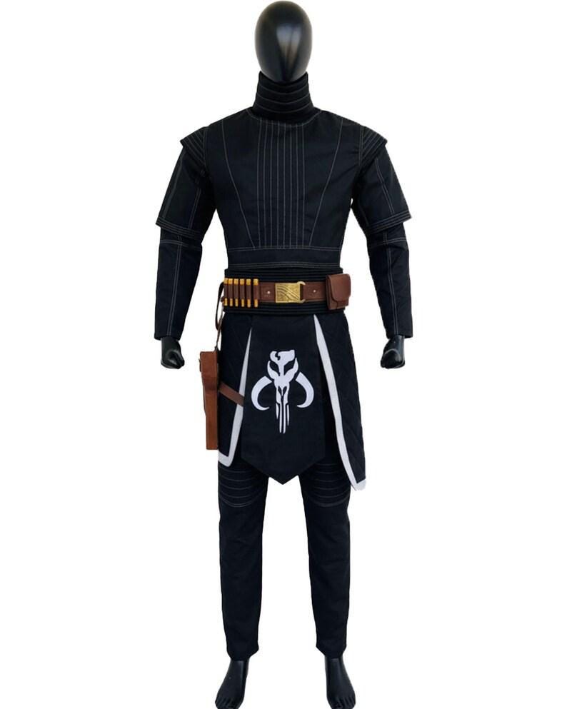 May include: A black costume set featuring a high-neck long-sleeve top with vertical stitching, matching trousers, and a brown utility belt with gold accents. A black apron-style piece displays a white skull emblem, accompanied by a brown holster.