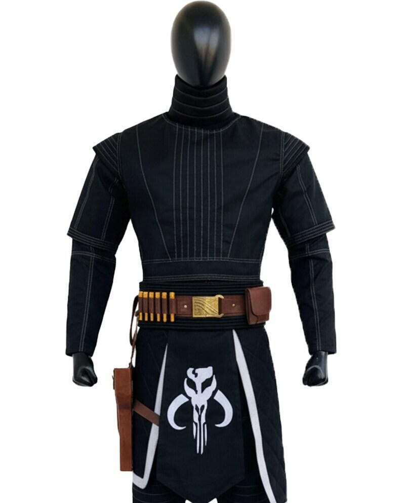 May include: A black long-sleeved tunic with vertical stitching, a high collar, and shoulder padding. A brown leather belt features gold-colored ammunition loops, a metallic buckle, and a holster. A black apron displays a white skull emblem.