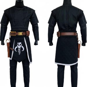 May include: A black costume set featuring a high-neck tunic with white stitching, matching trousers, and a quilted apron with a white Mythosaur skull emblem. Includes a brown utility belt with gold accents, ammunition loops, and a side holster.