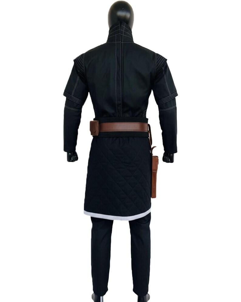 May include: A black long-sleeved tunic with a high collar and white stitching details, paired with a brown leather belt featuring a pouch and holster. The lower section of the tunic has a quilted texture and a white hem, worn over black trousers.