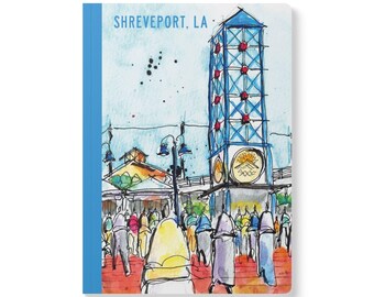 May include: A notebook with a watercolor illustration of a clock tower in Shreveport, LA. The tower is blue with red accents, and the scene includes people and buildings. The text "SHREVEPORT, LA" is at the top.