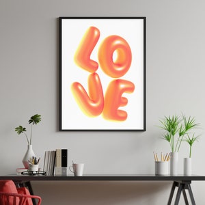 Puede incluir: Una impresi&oacute;n enmarcada con la palabra "LOVE" en letras grandes, 3D, naranja y amarillas sobre un fondo blanco.